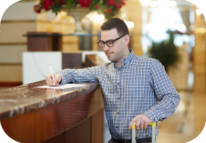 Mann i hotellresepsjon undertegner et dokument.